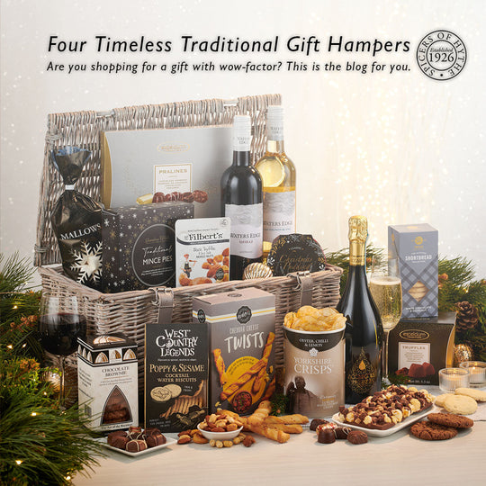 the blog cover to the latest blog from Spicers of Hythe on luxury traditional gift hampers. The image features an open hamper basket bursting with prosecco, wine, crisps & other luxury artisan goods. It is sat on a white and silver table top.